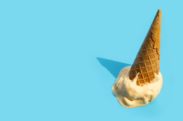 Derretendo bolas de sorvete com cone de waffle em fundo azul