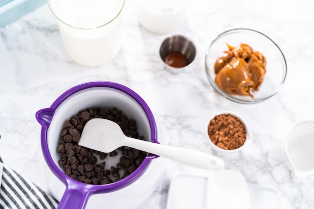 Derretendo pedaços de chocolate em caldeirão de doces para fazer sorvete de chocolate.