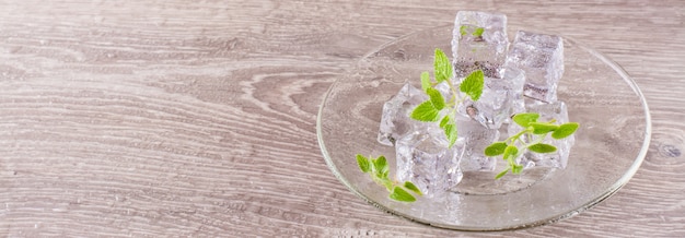 Derritiendo cubitos de hielo y hojas de menta en un plato sobre una mesa de madera