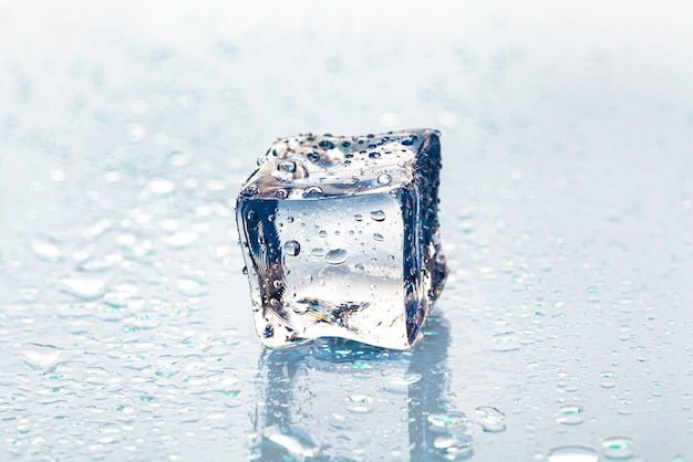 Foto derritiendo el cubo de hielo sobre la mesa húmeda