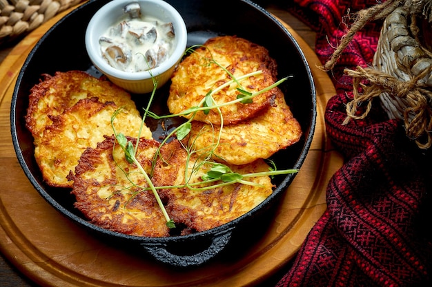 Deruny ucraniano tradicional com carne em uma panela preta Cozinha ucraniana Panqueca de batata Close-up