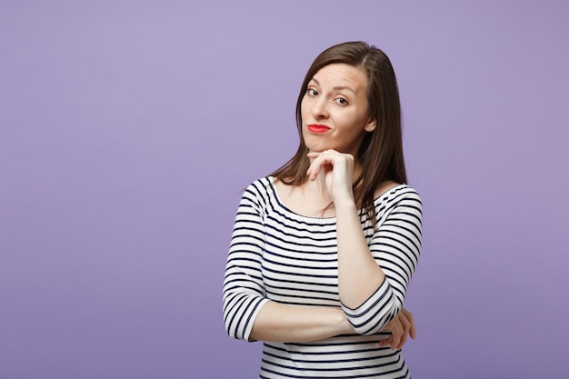 Desagradou enojado jovem morena em roupas listradas casuais posando isolado no retrato de estúdio de fundo roxo violeta. Conceito de estilo de vida de pessoas. Mock up espaço de cópia. Coloque o apoio de mão no queixo.