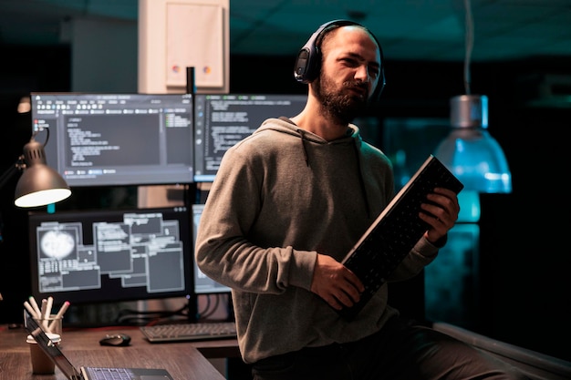 Desarrollador alegre jugando con el teclado tocando la guitarra, trabajando en la interfaz de usuario con el algoritmo de análisis de múltiples pantallas en la agencia de software. Escritura de código y servidor de programación.