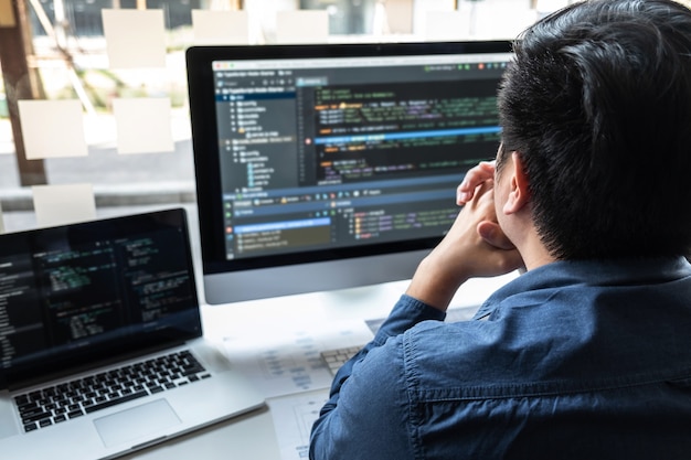 Desarrollador programador que trabaja en un proyecto en computadora de desarrollo de software en la oficina de la empresa de TI, escribiendo códigos y sitios web de códigos de datos y tecnologías de base de datos de codificación para encontrar una solución al problema.