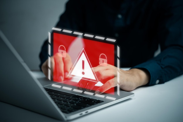 Desarrollador de programadores de empresarios que usa una computadora portátil con un sistema de señal de advertencia de precaución triangular pirateado en la vulnerabilidad de ciberseguridad de la red informática