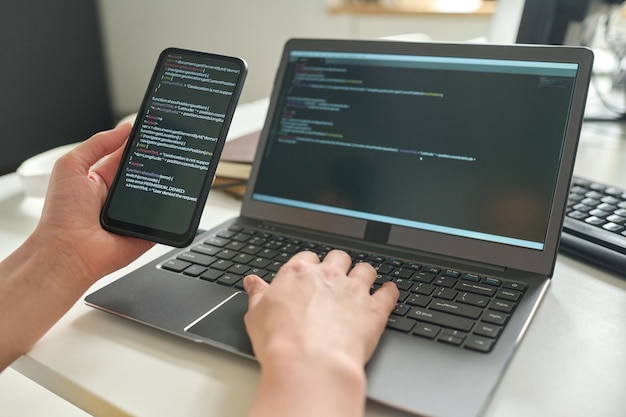 Desarrollador que conecta el teléfono inteligente con la computadora portátil