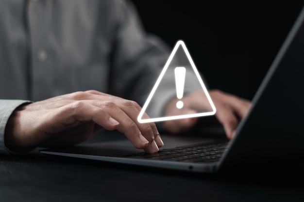 Desarrollador que utiliza una computadora portátil con signo de triángulo de advertencia para la notificación de errores y el concepto de mantenimiento