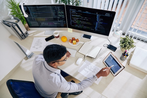 Desarrollador de software que verifica el calendario en la tableta al planificar el trabajo en el código de programación para un gran proyecto