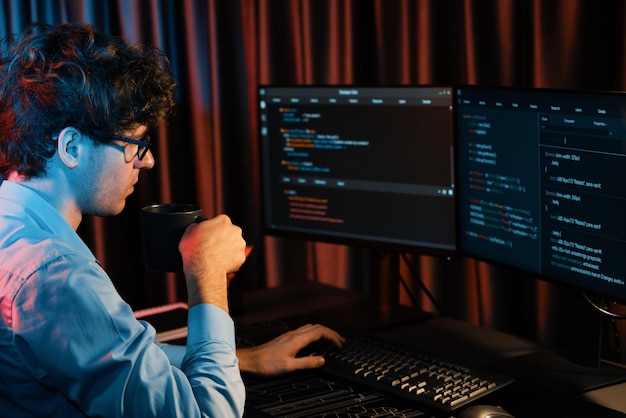 Desarrollador de TI concentrándose en software mientras bebe café a la luz de neón Gusher