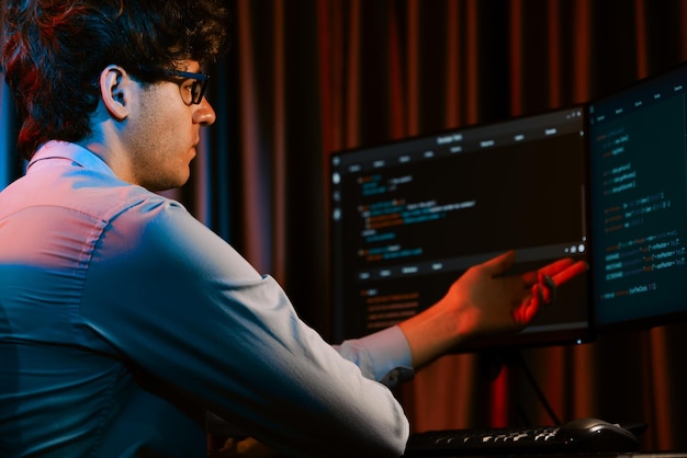 Desarrollador de TI que trabaja concentrando software en línea en la sala de luces de neón Gusher
