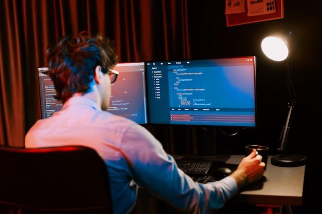 Desarrollador de TI que trabaja concentrando software en línea en la sala de luces de neón Gusher