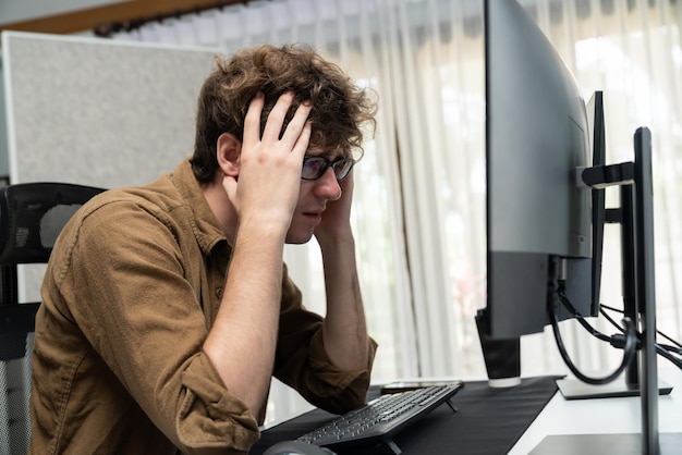 Desarrollador de TI que trabaja con estrés sobrecargado de trabajo en la creación de codificación en la pantalla del ordenador en la última versión de la aplicación en el sitio web en línea en un gran proyecto que tiene dolor de cabeza en una mala sensación en la oficina de casa Gusher