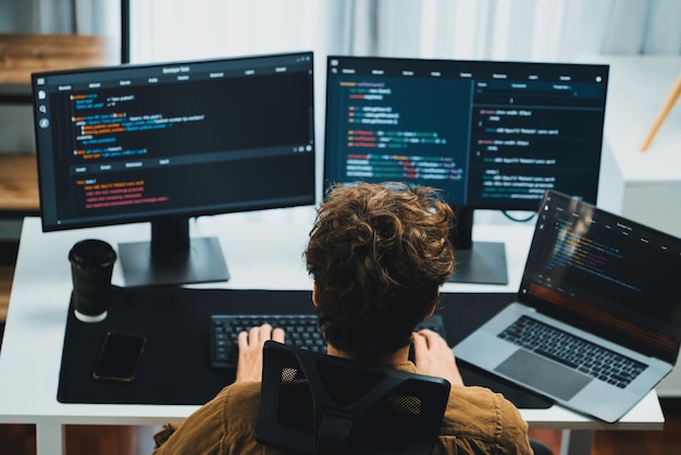 Desarrollador de TI que trabaja en línea desarrollo de software codificación en pantallas de PC Gusher