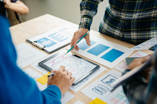 El desarrollador de UX y el diseñador de ui hacen una lluvia de ideas sobre el diseño de estructura alámbrica de la interfaz de la aplicación móvil con el código de color y el resumen del cliente en la oficina modernaxA