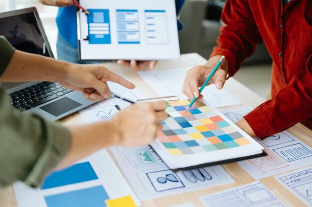 El desarrollador de UX y el diseñador de UI hacen una lluvia de ideas sobre el diseño de estructura alámbrica de la interfaz de la aplicación móvil con el resumen del cliente y el código de color en officexA