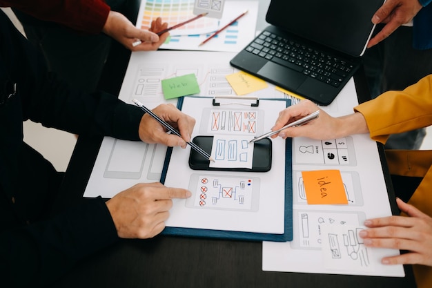 Desarrollador de UX y diseñador de UI haciendo una lluvia de ideas sobre el diseño de wireframe de la interfaz de la aplicación móvil con el breif del cliente y el código de color en la oficina moderna