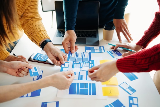 Desarrollador de UX y diseñador de UI haciendo una lluvia de ideas sobre el diseño de wireframe de la interfaz de la aplicación móvil con el breif del cliente y el código de color en la oficina moderna