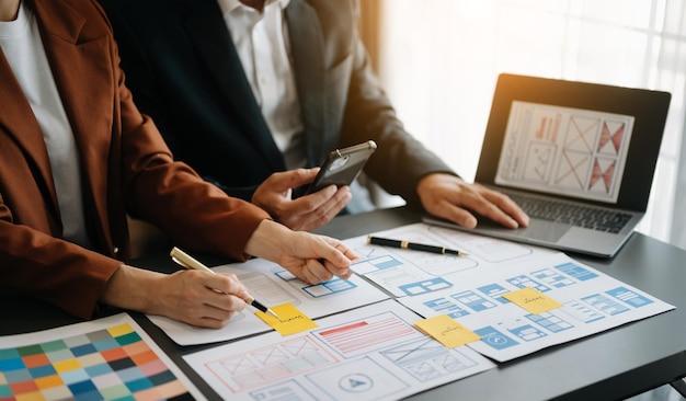 Desarrollador de UX y diseñador de UI haciendo una lluvia de ideas sobre el diseño de wireframe de la interfaz de la aplicación móvil con el breif del cliente y el código de color en la oficina moderna