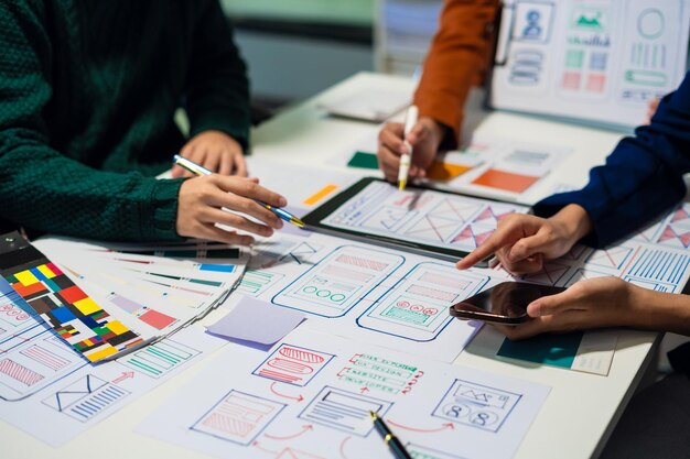 Desarrollador de UX y diseñador de UI haciendo una lluvia de ideas sobre el diseño de wireframe de la interfaz de la aplicación móvil con el breif del cliente y el código de color en la oficina
