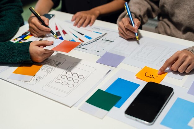 Desarrollador de UX y diseñador de UI haciendo una lluvia de ideas sobre el diseño de wireframe de la interfaz de la aplicación móvil con el breif del cliente y el código de color en la oficina
