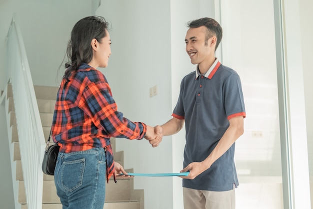 Desarrollador de viviendas de empresario entregando certificado de vivienda a mujer hermosa mientras se da la mano en la casa