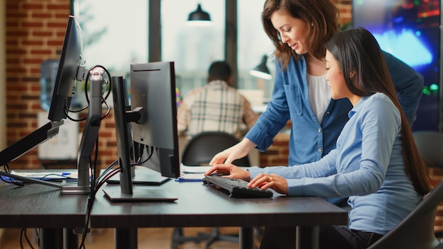 Desarrolladoras de aplicaciones que trabajan en la producción de software con múltiples pantallas, utilizando la interfaz de las computadoras para desarrollar nuevo contenido profesional. Trabajadores de agencias creativas creando un proyecto de escena 3d.