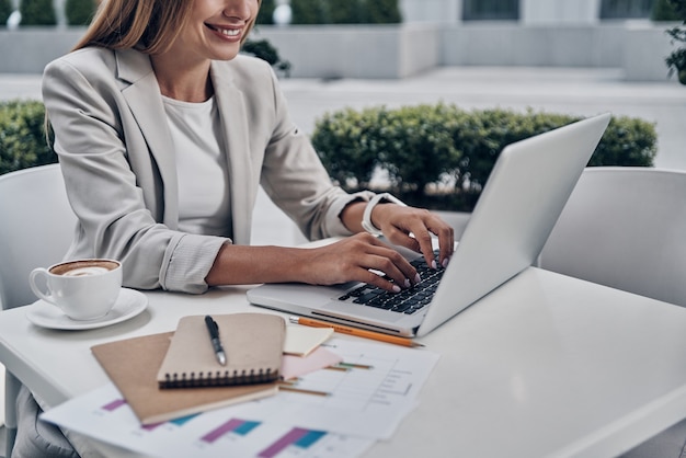 Desarrollo de nueva estrategia empresarial. Cerrar vista superior de mujer joven usando laptop y sonriendo