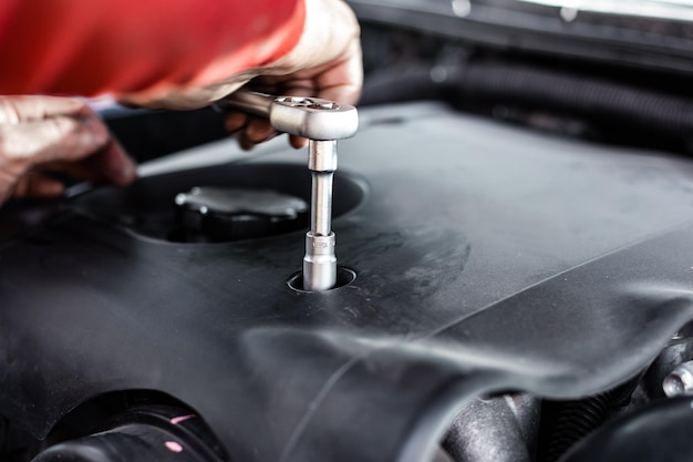 Desatornillar la cubierta del motor del vehículo para mantenimiento y reparación