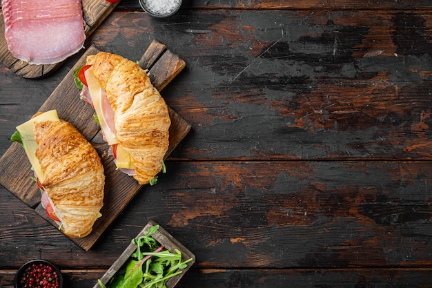 Desayuno, almuerzo de negocios, sándwiches Croissant set, con hierbas e ingredientes, sobre fondo de mesa de madera oscura vieja, vista superior plana, con espacio para copiar texto