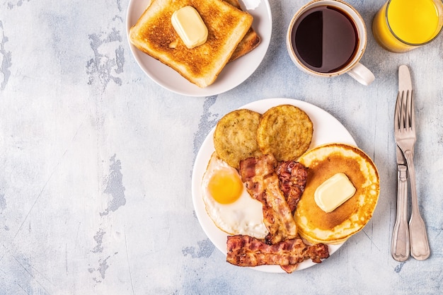 Desayuno americano completo saludable con huevos, tocino, panqueques y latkes, vista superior.