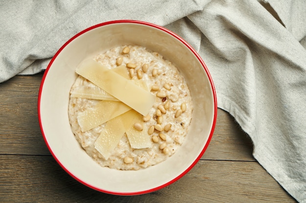 Desayuno apetitoso y saludable - avena con queso parmesano en un recipiente sobre una superficie de madera. De cerca. Copia espacio