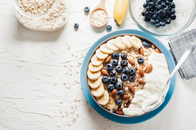 Desayuno, avena con arándanos, almendras y yogur en un tazón de la mañana.