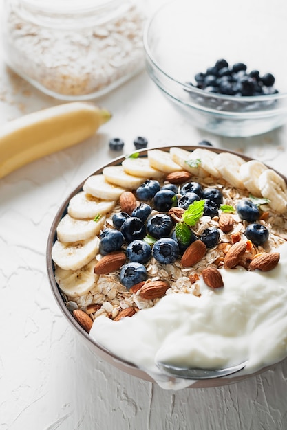 Desayuno, avena con arándanos, almendras y yogur en un tazón de la mañana.