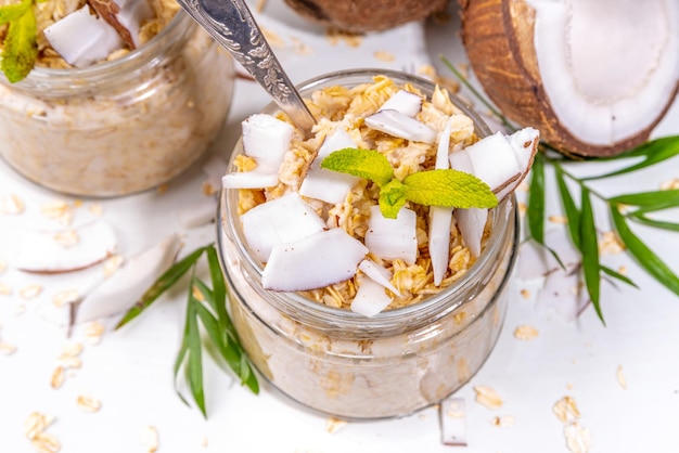 Desayuno avena avena con leche de coco y trozos de coco fresco Dieta comida saludable dieta vegana Sobre fondo claro con cocos frescos y hojas de palma copia espacio