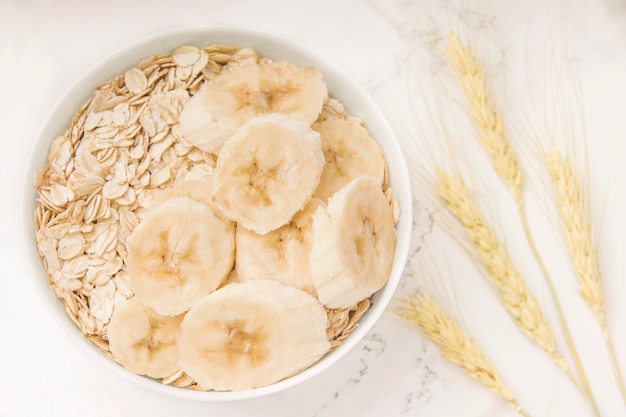 Desayuno avena con plátano sobre un fondo blanco.