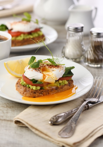 Desayuno. Best Eggs Benedict sobre una rebanada de pan de cereal tostado con guacamole y espinacas