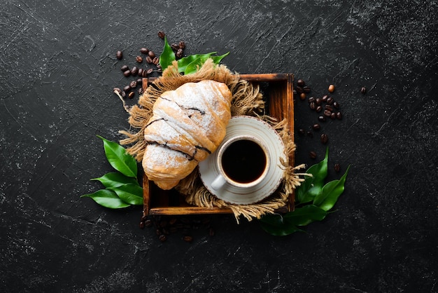 Desayuno Café croissant y macarrones Sobre un fondo de piedra negra Vista superior Espacio libre para su texto