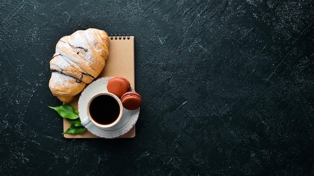 Desayuno Café croissant y macarrones Sobre un fondo de piedra negra Vista superior Espacio libre para su texto