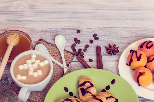 Desayuno de café, croissants, albaricoques, miel, canela y anís.