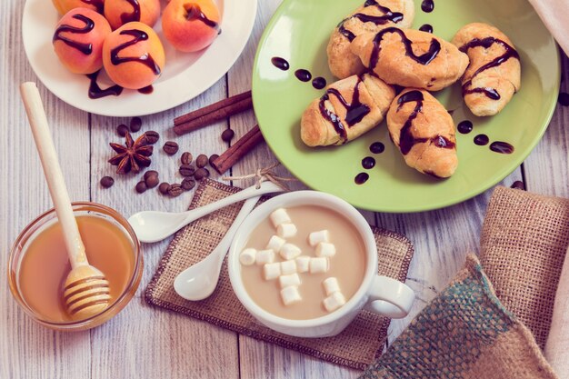 Desayuno de café, croissants, albaricoques, miel, canela y anís.