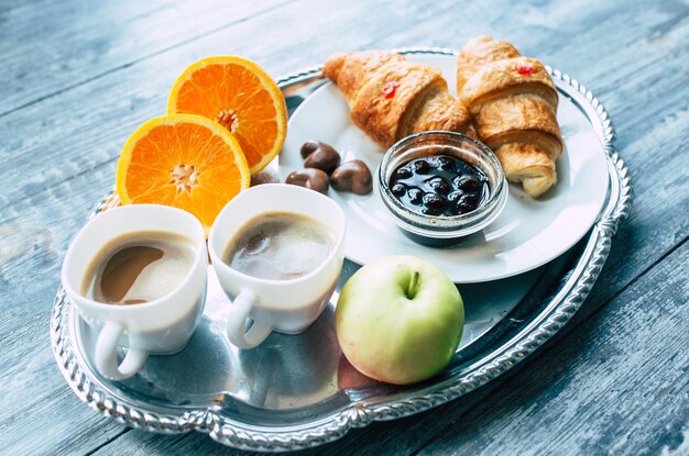 Desayuno con café, croissants, caramelos de manzana, naranja y chocolate