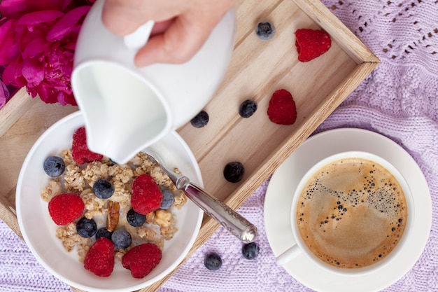 Desayuno con café, granola, moras y leche.