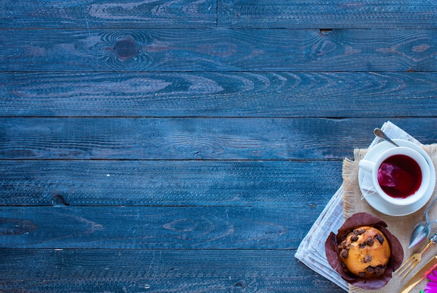 Desayuno con café y té con diferentes pasteles y frutas en una mesa de madera.