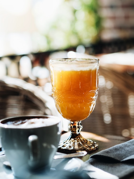 Desayuno en la cafetería. Una taza de capuchino y jugo fresco.