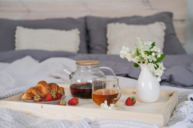 Desayuno en la cama Bandeja con croissant de té y fresas en la cama del dormitorio