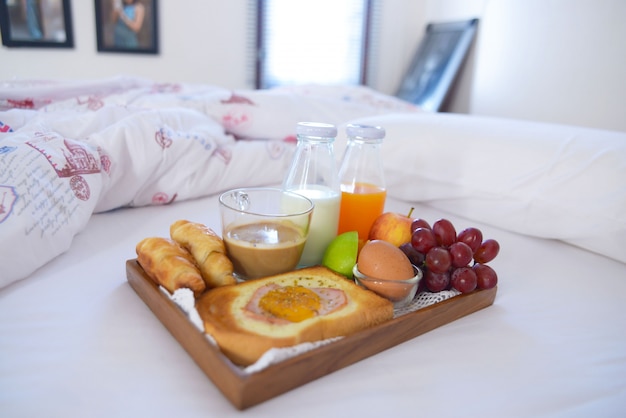 Desayuno en la cama con café, croissants, luz de la ventana.
