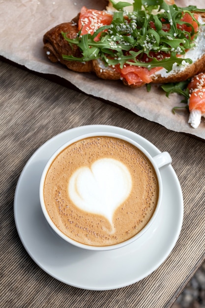 Desayuno con capuchino y bollo en la cafetería. Mañana americana. Croissant con trucha y rúcula