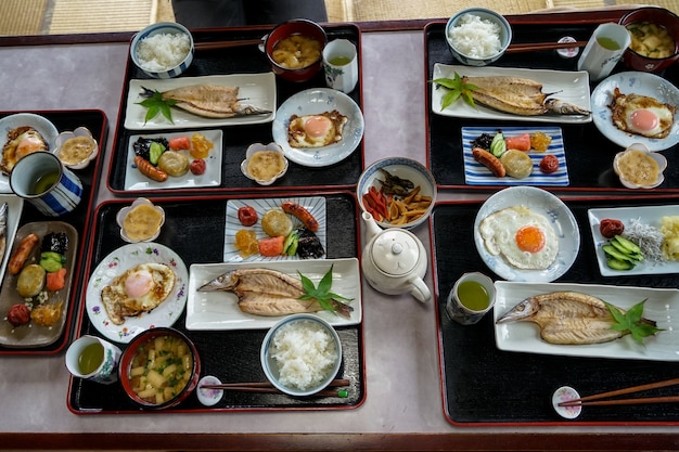 Desayuno en una casa de familia japonesa que incluye arroz blanco, pescado a la parrilla, huevo frito, guarniciones