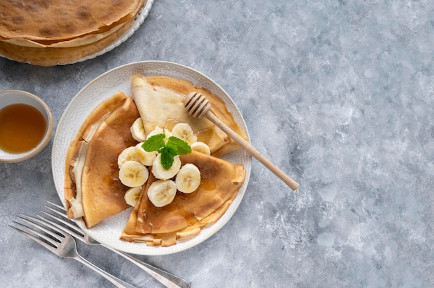 Desayuno con cepes recién horneados o tortitas finas, servido con miel y taza de té caliente