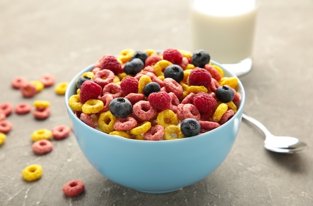 Desayuno con cereales, leche y bayas sobre fondo gris. Vista superior. Foto vertical